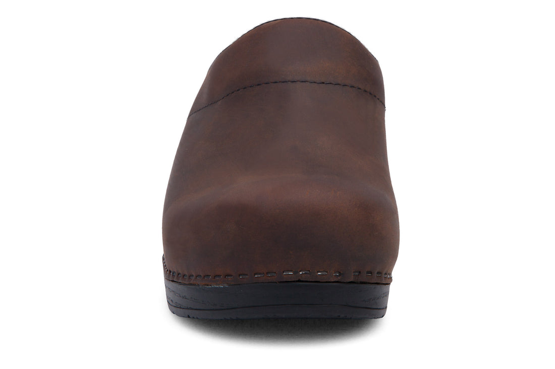 Clog, brown leather, closed toe, open heel; Dansko Karl mens with plantar fasciitis support and black sole, side view.
