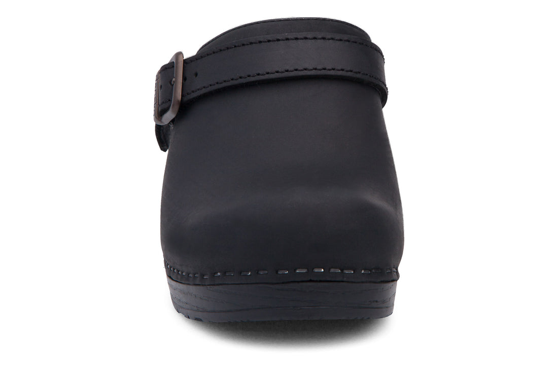 Clog, black leather, Dansko Ingrid sling-back with strap, highlighted stitching on sole, comfort support visible.