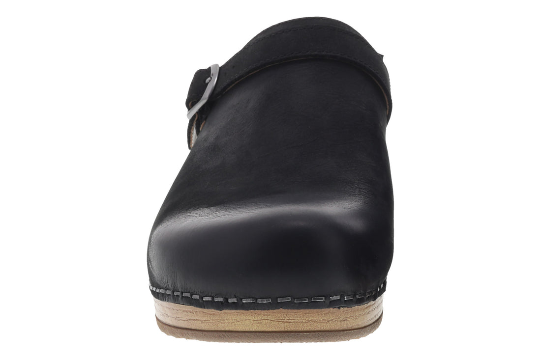 Mule shoe, black leather, Dansko Berry with side buckle, wooden sole, white stitching. Comfort features not visible.